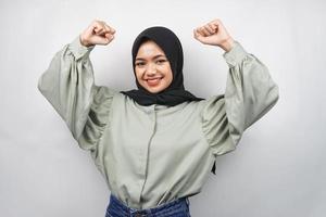 bella giovane donna musulmana asiatica sicura e sorridente, con il pugno chiuso, pugni, segno per lo spirito, combattimento, segno di vittoria, isolato su sfondo grigio