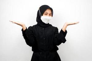 donna musulmana che sorride con sicurezza con i palmi aperti, presentando qualcosa, presentando un prodotto, isolato su sfondo bianco