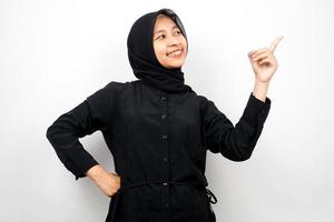 bella e allegra giovane donna musulmana asiatica, con la mano che punta allo spazio vuoto, presentando qualcosa, isolata su sfondo bianco