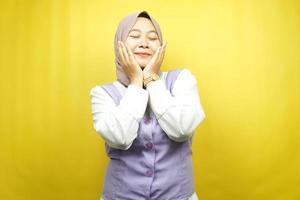 bella giovane donna musulmana asiatica sorridente felice, carina, sentirsi a proprio agio, sentirsi curata, sentirsi bene, con le mani che tengono le guance isolate su sfondo giallo foto