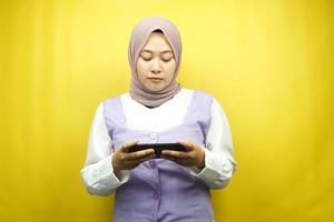 bella giovane donna musulmana asiatica con smartphone che tiene in mano, gioco, triste, sconfitta, infelice, isolato su sfondo giallo, concetto pubblicitario foto