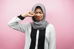 bella giovane donna musulmana che piange, mani che asciugano lacrime, isolata su sfondo rosa foto