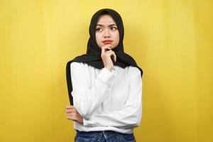 bella giovane donna musulmana asiatica che pensa, c'è un problema, si sente strano, qualcosa non va, cerca una soluzione, isolata su sfondo giallo foto
