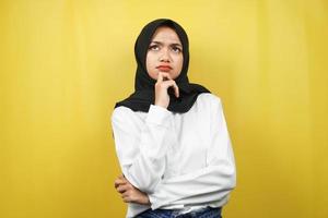 bella giovane donna musulmana asiatica che pensa, cerca idee, cerca soluzioni ai problemi, con le mani che tengono il mento, isolato su sfondo giallo foto