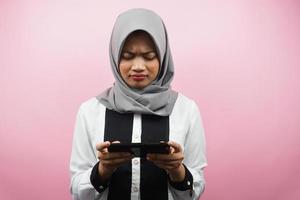bella giovane donna musulmana asiatica con smartphone che tiene in mano, gioco, triste, sconfitta, infelice, isolato su sfondo rosa, concetto pubblicitario