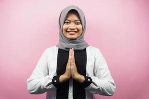 bella giovane donna musulmana asiatica con le mani sul viso, scusandosi, sentendosi in colpa, eid ul fitr e eid ul adha, sorridente sicura di sé, entusiasta e allegra, di fronte alla telecamera isolata su sfondo rosa foto
