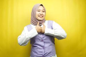 bella giovane donna musulmana asiatica con le mani pollice in alto, segno ok, buon lavoro, successo, vittoria, sorridente fiducioso, entusiasta e allegro, guardando la telecamera isolata su sfondo giallo foto