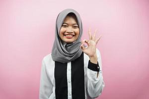 bella giovane donna musulmana asiatica sorridente sicura di sé, entusiasta e allegra con le mani segno ok, successo, buon lavoro, segno di successo, isolato su sfondo rosa foto