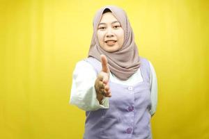 bella giovane donna musulmana asiatica sorridente con fiducia, con le mani che stringono la macchina fotografica, segno di cooperazione con le mani, segno di accordo con la mano, segno di amicizia con la mano, isolato su sfondo giallo