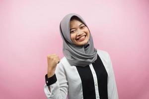 bella giovane donna musulmana asiatica sorridente sicura di sé, entusiasta e allegra con le mani serrate, segno di successo, pugni, combattimenti, non paura, vittoria, isolata su sfondo rosa