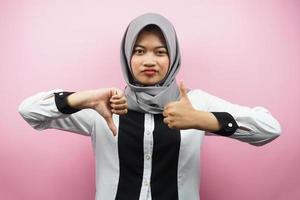 bella asiatica giovane donna musulmana con segno di mano come o antipatia, sì o no, felice o triste, confrontando due cose, isolato su sfondo rosa