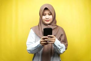 bella asiatica giovane donna musulmana che tiene smartphone isolato su sfondo giallo