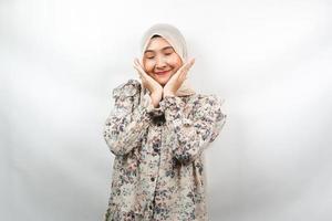 bella giovane donna musulmana asiatica sorridente felice, carina, sentirsi a proprio agio, sentirsi curata, sentirsi bene, con le mani che tengono le guance isolate su sfondo bianco