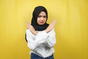 bella giovane donna musulmana asiatica con le braccia incrociate, mani che mostrano rifiuto, mani che mostrano divieto, mani che mostrano disapprovazione, isolate su sfondo giallo foto