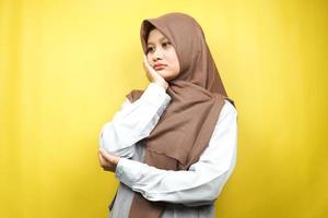 bella giovane donna musulmana asiatica che pensa, cerca idee, cerca soluzioni ai problemi, con le mani che tengono le guance, isolate su sfondo giallo