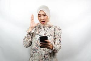 bella giovane donna musulmana asiatica scioccata, sorpresa, con le mani che tengono smartphone, guardando smartphone, guardando promo, isolato su sfondo bianco, concetto pubblicitario