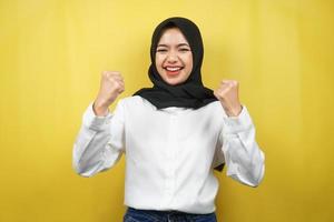 bella giovane donna musulmana asiatica sorridente sicura di sé, entusiasta e allegra con le mani serrate, segno di successo, pugni, combattimenti, non paura, isolata su sfondo giallo foto