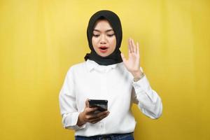 bella giovane donna musulmana asiatica scioccata, sorpresa, con le mani che tengono smartphone, guardando smartphone, guardando promo, isolato su sfondo giallo, concetto pubblicitario