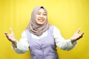 bella giovane donna musulmana asiatica che sorride allegramente, con le braccia aperte alla telecamera, segno di benvenuto mano, segno della mano che vuole abbracciare, isolato su sfondo giallo