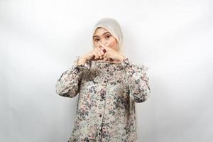 bella giovane donna musulmana asiatica con il dito sulla bocca, dicendo di stare zitta, non fare rumore, abbassare la voce, non parlare, isolata su sfondo bianco