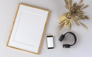 smartphone, cuffie, cornice per foto e vaso su sfondo bianco
