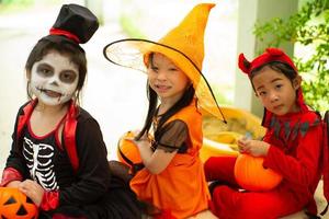 ritratto di sorelle felici in costume di halloween seduto davanti alla porta e in attesa di giocare dolcetto o scherzetto. buon giorno di halloween foto