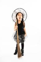 ritratto bambina asiatica vestirsi in strega carina per costume di halloween con scopa e sfondo isolato