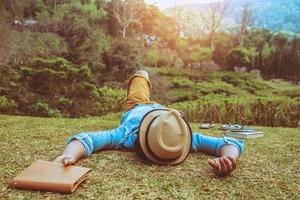 natura di viaggio uomo asiatico. viaggiare rilassati. dormire sul prato del parco. in estate. foto