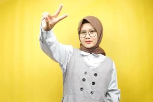 bella giovane donna musulmana asiatica che fa il broncio con le mani firmate con V, ok, buon lavoro, accordo, vittoria, guardando la telecamera isolata su sfondo giallo
