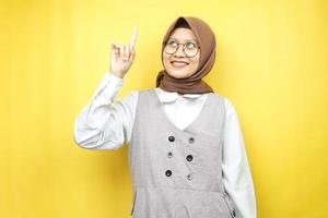 bella giovane donna musulmana asiatica sorridente sicura di sé, entusiasta e allegra con le mani rivolte verso l'alto, ottenere idee, trovare soluzioni, presentare qualcosa, isolato su sfondo giallo