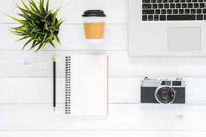 spazio di lavoro minimo - foto creativa piatta della scrivania dell'area di lavoro. scrivania da ufficio vista dall'alto con laptop, taccuini mock up e pianta su sfondo bianco in legno. vista dall'alto con spazio di copia, fotografia piatta