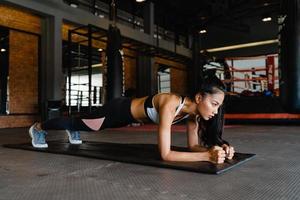 felice giovane donna asiatica esercizio facendo allenamento brucia grassi della plancia in classe di fitness. atleta con confezione da sei, attività ricreativa sportiva, allenamento funzionale, concetto di stile di vita sano. foto