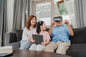 nonni e nipoti asiatici che usano la realtà virtuale e il tablet giocano a casa. cinese anziano, nonno e nonna felice rilassarsi con la ragazza sdraiata sul divano nel concetto di soggiorno. foto