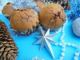 cupcakes con cono di abete di latte condensato e stella di natale con perline trasparenti su sfondo blu foto