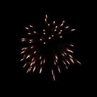 i fuochi d'artificio arancioni scoppiano nell'aria illuminano il cielo con uno spettacolo abbagliante e colorati festival di fuochi d'artificio su fondo nero. foto
