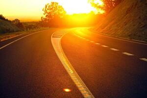 tramonto arancione sulla strada pista bella strada che gira tra le colline e la strada di montagna strada dei prati la sera in. foto