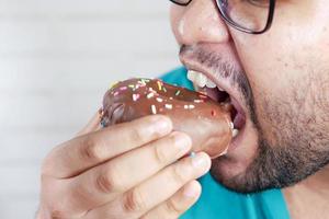 primo piano di un giovane che mangia ciambella, foto