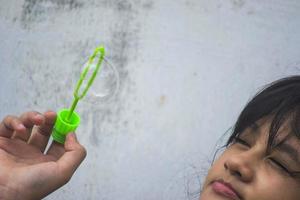 una ragazza che tiene in mano un creatore di bolle e le fa esplodere. foto