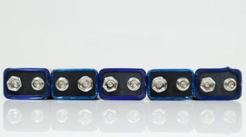 cinque batterie blu pp3 usate allineate su uno sfondo bianco con la riflessione. batteria principale per alimentatori personali. primo piano di un connettore della batteria graffiato e usato. foto