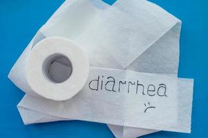 un rotolo di carta igienica bianca con l'etichetta diarrea su sfondo blu. avvicinamento. foto