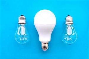 lampada a risparmio energetico con lampade ad incandescenza in fila su sfondo blu. il concetto di risparmio energetico. foto
