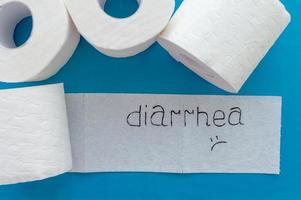 rotoli di carta igienica bianca con etichetta diarrea su sfondo blu. avvicinamento. foto