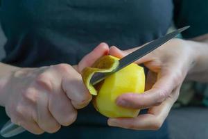 le mani delle donne che sbucciano le patate foto