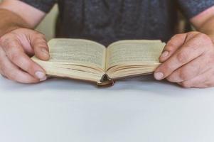 uomo che legge un libro a tavola, fa uno spuntino mentre legge, una breve pausa foto