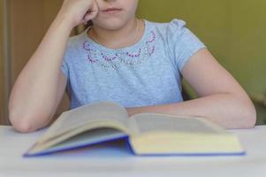 bambino che legge un libro a tavola foto