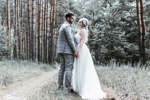 gli sposi si abbracciano nella foresta il giorno del matrimonio. cerimonia matrimoniale. messa a fuoco selettiva. grana della pellicola. foto