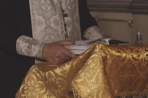 le mani del sacerdote sulla Bibbia durante la lettura delle preghiere. la cerimonia del battesimo. avvicinamento. foto