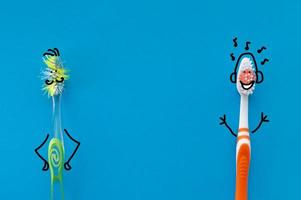 spazzolino da denti nuovo e vecchio sotto forma di personaggi dei cartoni animati su sfondo blu. la vista dall'alto. il concetto di salute dentale. foto