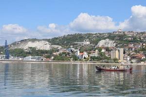 paesaggio urbano dalle acque del mar nero in bulgaria. pescatori che vanno in mare in barca. bella destinazione di viaggio e vacanza. acqua cristallina increspata e morbido cielo blu. foto