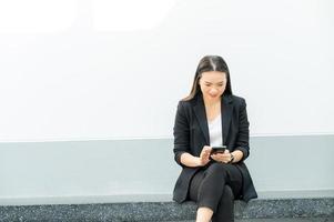 donna lavoratrice asiatica che tiene un telefono cellulare in piedi in ufficio donna che lavora concetto donna d'affari in aula tecnologia foto